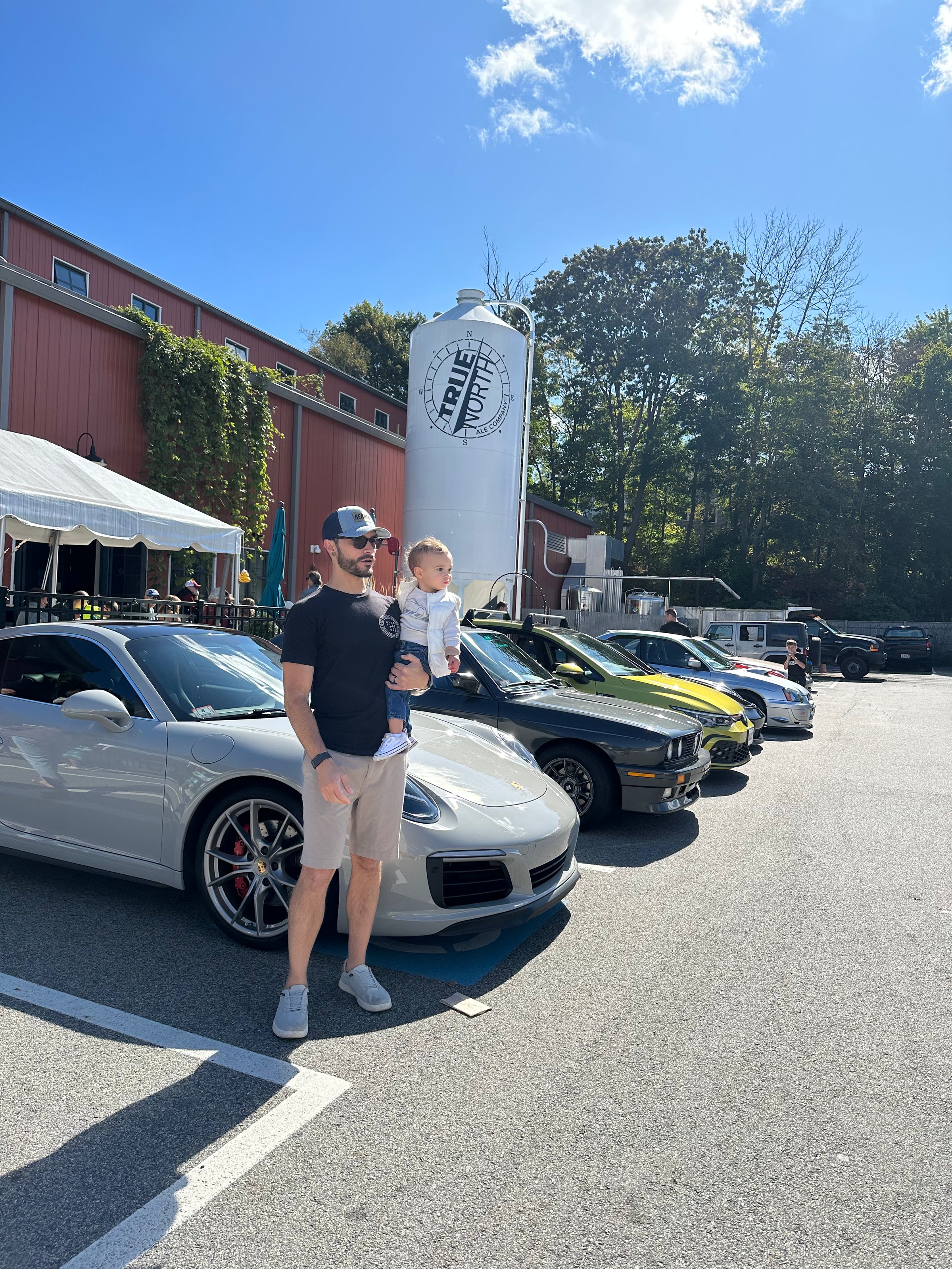 Dad Driven founder holding his little driver at a car show he put together with over 300 cars | Where speed meets fatherhood